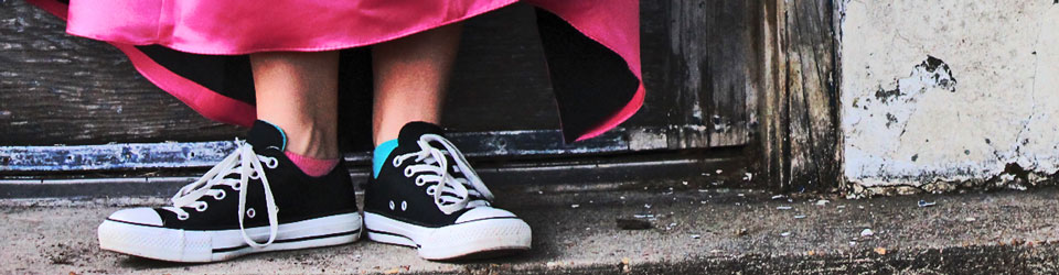 A girl wearing black Converse trainers and a shocking pink ball dress.
